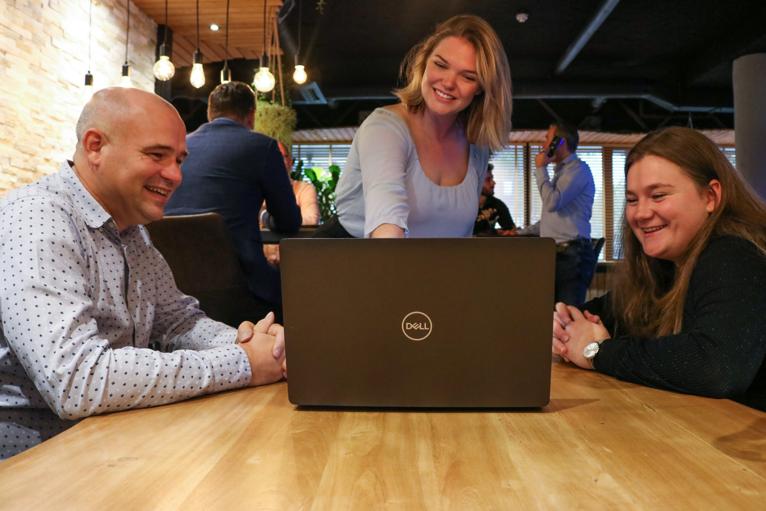 Vrouw legt aan twee collega's iets uit op de laptop door te wijzen naar het scherm